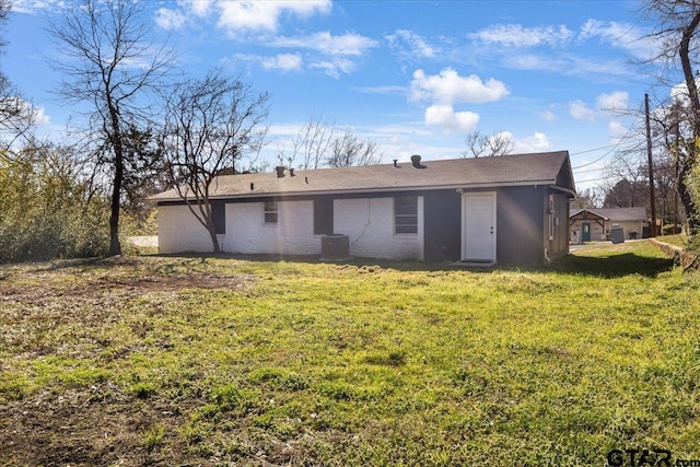 back of house with central AC unit and a yard