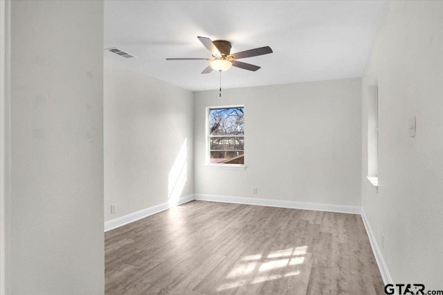 unfurnished room with visible vents, ceiling fan, baseboards, and wood finished floors