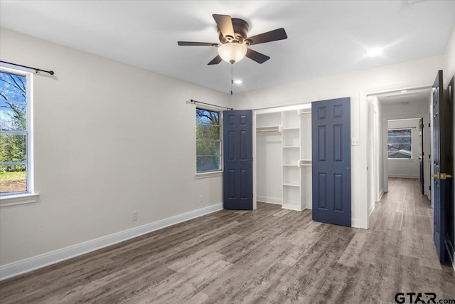 unfurnished bedroom with ceiling fan, a closet, wood finished floors, and baseboards