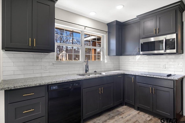 kitchen featuring light stone counters, light wood-type flooring, a sink, and black appliances