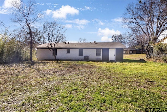 rear view of property featuring a lawn and central air condition unit