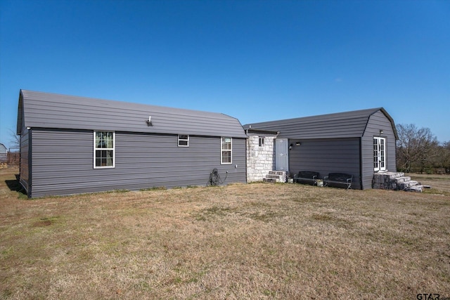 rear view of house with entry steps and a yard