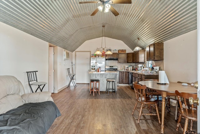 dining area featuring wood finished floors, a ceiling fan, and vaulted ceiling