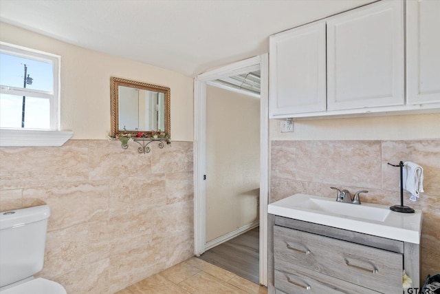 bathroom featuring toilet, tile walls, and vanity