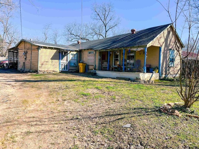 back of property with covered porch and a lawn