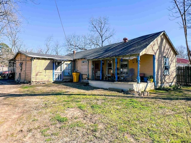 rear view of property featuring a yard, a porch, and fence