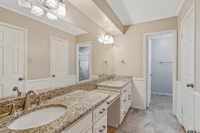 bathroom featuring a sink, double vanity, ornamental molding, and a shower stall