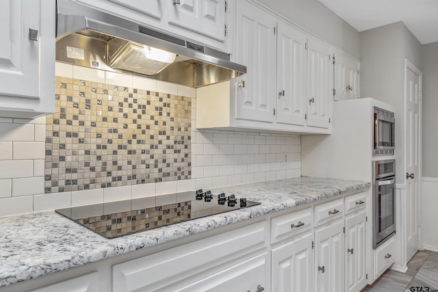 kitchen with under cabinet range hood, backsplash, white cabinetry, and stainless steel appliances