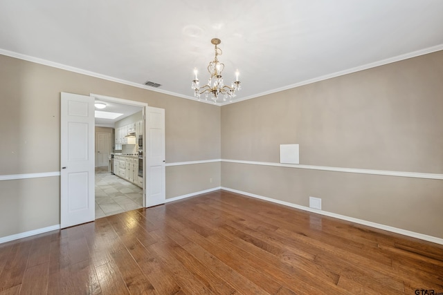 unfurnished room with baseboards, visible vents, hardwood / wood-style flooring, crown molding, and a chandelier