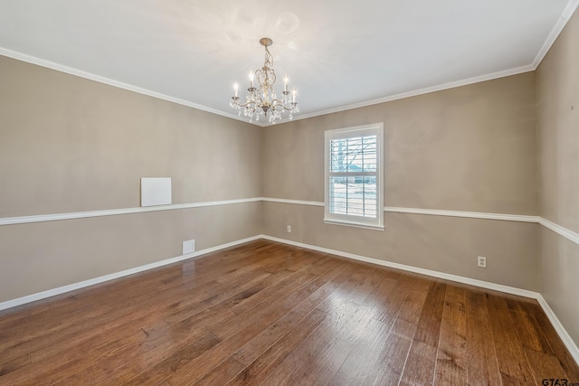 empty room with a notable chandelier, ornamental molding, baseboards, and hardwood / wood-style floors