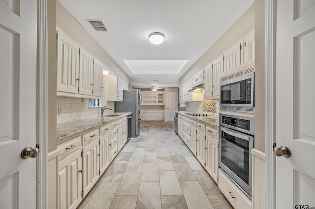 kitchen featuring visible vents, a sink, tasteful backsplash, stainless steel appliances, and a skylight