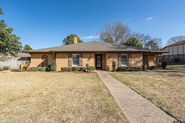 single story home with fence, a front yard, a shingled roof, brick siding, and a chimney