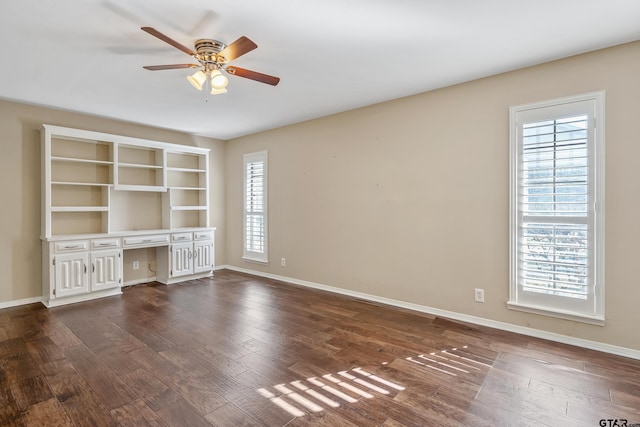 unfurnished living room with baseboards, ceiling fan, dark wood-style flooring, and built in study area