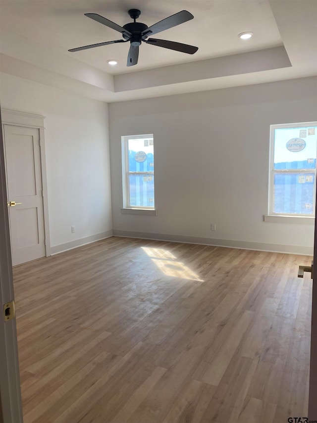 unfurnished room featuring ceiling fan, light hardwood / wood-style floors, and a raised ceiling