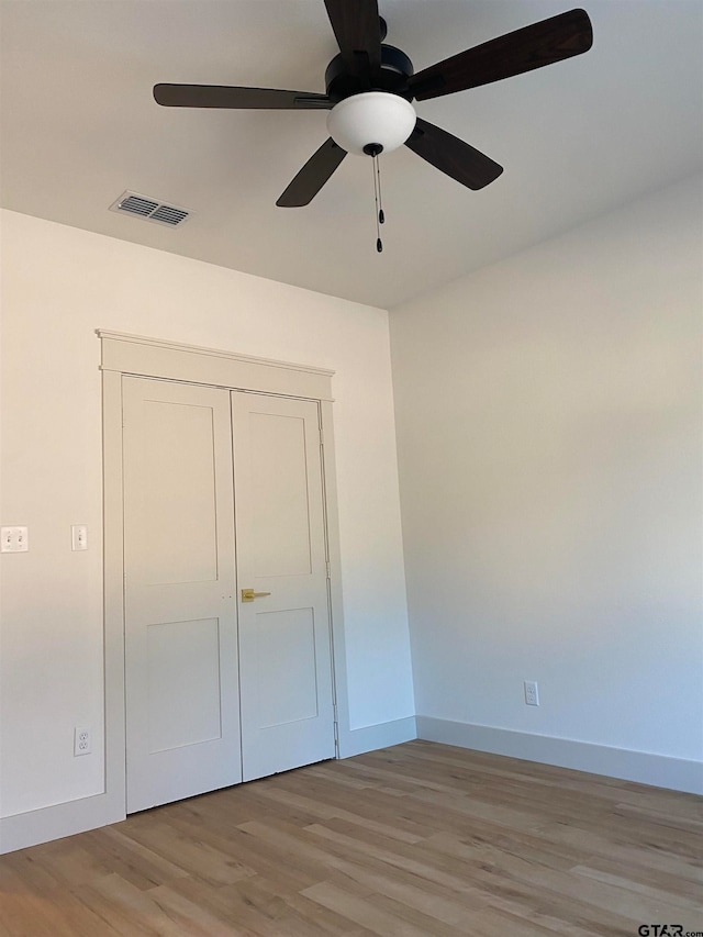 unfurnished bedroom with light hardwood / wood-style floors, ceiling fan, and a closet