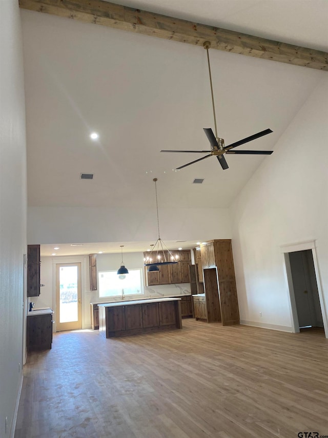 unfurnished living room with light hardwood / wood-style floors, ceiling fan with notable chandelier, beam ceiling, and high vaulted ceiling