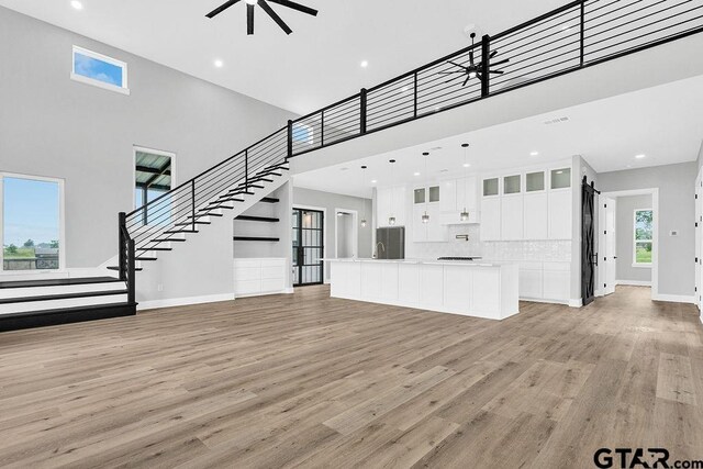 3255 Vz County Road 2120, Canton, TX 75103 - unfurnished living room with a ceiling fan, a towering ceiling, light wood-style floors, baseboards, and stairs