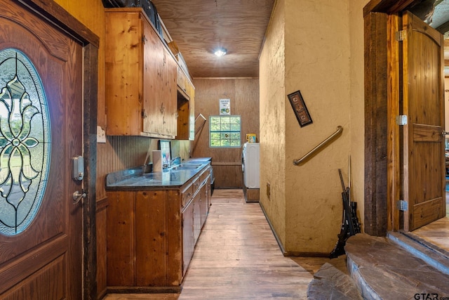 2711 N Fm 250, Hughes Springs, TX 75656 - kitchen featuring a textured wall, washer / dryer, light wood finished floors, dark countertops, and brown cabinets