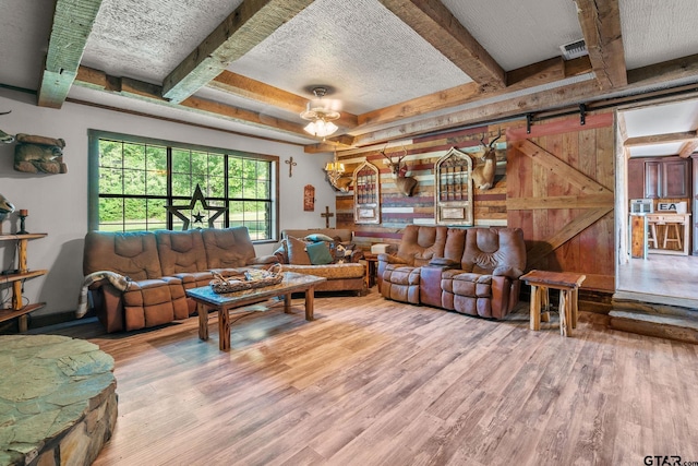 2711 N Fm 250, Hughes Springs, TX 75656 - living area featuring wood finished floors, beam ceiling, a textured ceiling, and a barn door