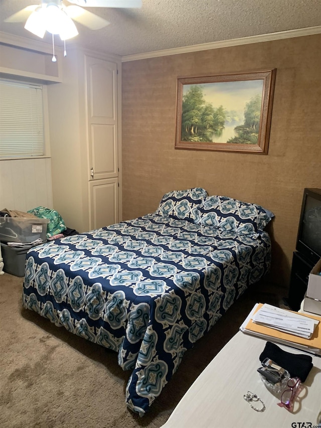 bedroom with carpet floors, a textured ceiling, ceiling fan, and crown molding