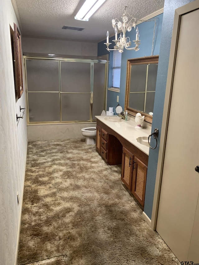 full bath with a sink, double vanity, toilet, a textured ceiling, and bath / shower combo with glass door