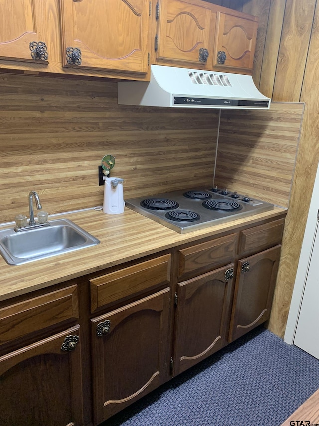 kitchen with a sink, ventilation hood, butcher block countertops, stainless steel cooktop, and decorative backsplash