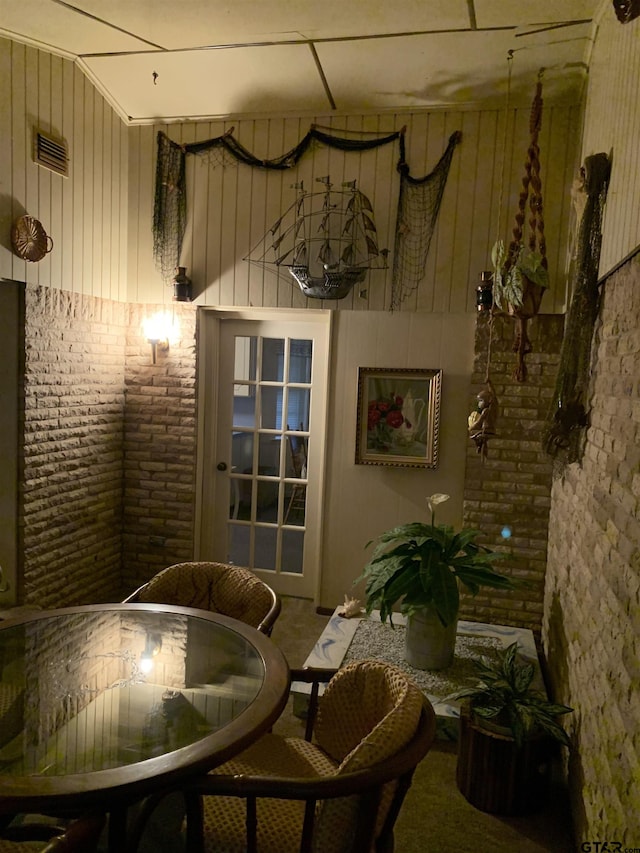 living area featuring visible vents, carpet flooring, and brick wall