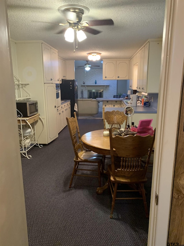 dining room with a ceiling fan, a textured ceiling, and dark carpet