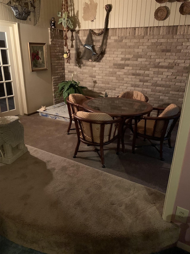 dining space featuring carpet flooring and brick wall