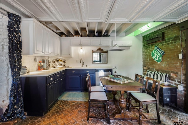 kitchen featuring stainless steel dishwasher, brick wall, blue cabinets, sink, and white cabinetry