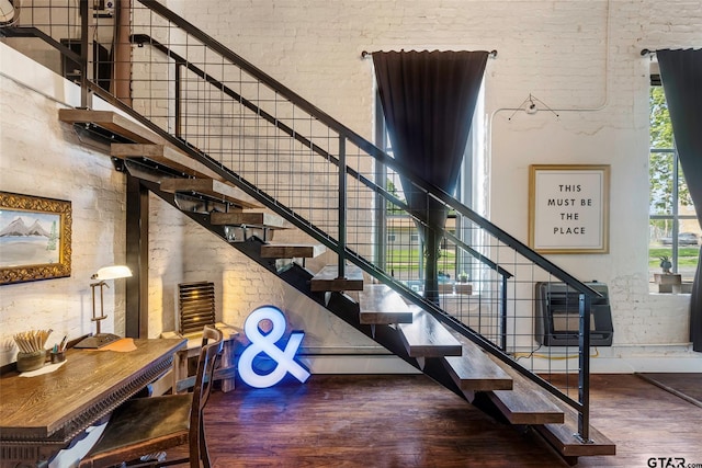 staircase with wood-type flooring and a high ceiling