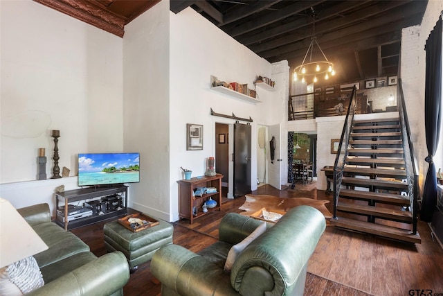 living room with a barn door, wood-type flooring, a high ceiling, and a notable chandelier