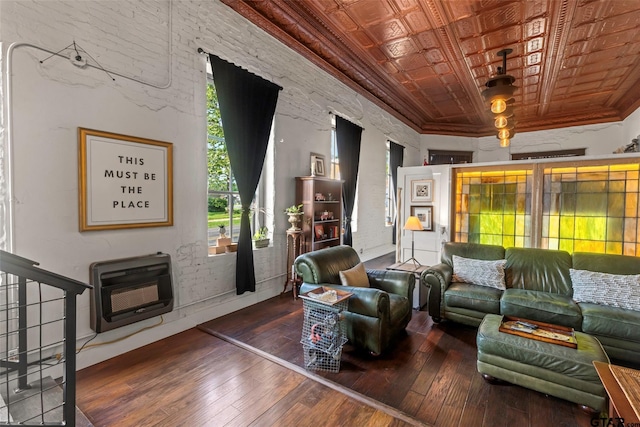 living room featuring heating unit, an ornate ceiling, crown molding, and wood finished floors