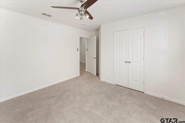 unfurnished bedroom featuring light colored carpet, a closet, and ceiling fan