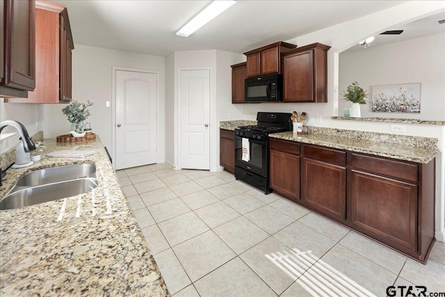 kitchen with light stone counters, sink, black appliances, and light tile patterned flooring