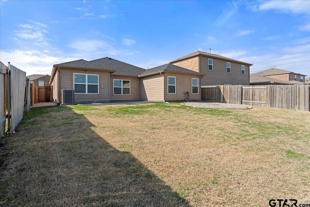 rear view of house with cooling unit and a yard