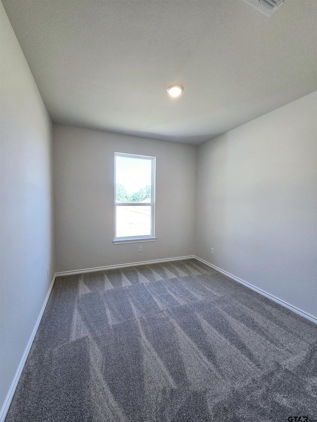 spare room with dark colored carpet and baseboards