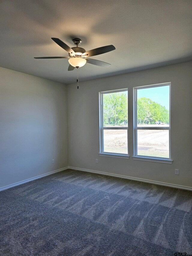 spare room with dark colored carpet, baseboards, and a ceiling fan