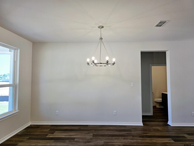 unfurnished dining area featuring a chandelier, dark wood-style floors, and baseboards