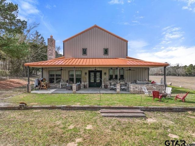 rear view of house with a lawn, a patio, a standing seam roof, french doors, and board and batten siding