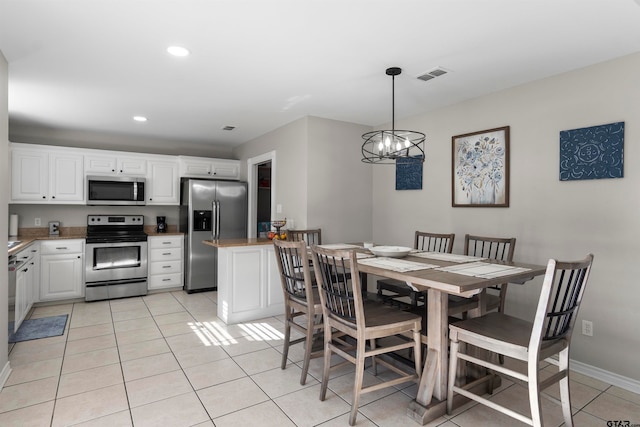 kitchen featuring stainless steel appliances, white cabinetry, light tile patterned floors, pendant lighting, and an inviting chandelier