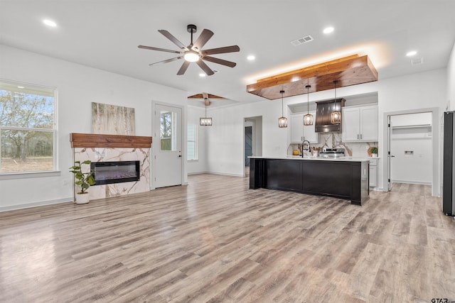 kitchen featuring a kitchen island with sink, plenty of natural light, white cabinets, and hanging light fixtures