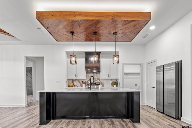 kitchen featuring white cabinetry, hanging light fixtures, an island with sink, light hardwood / wood-style floors, and appliances with stainless steel finishes