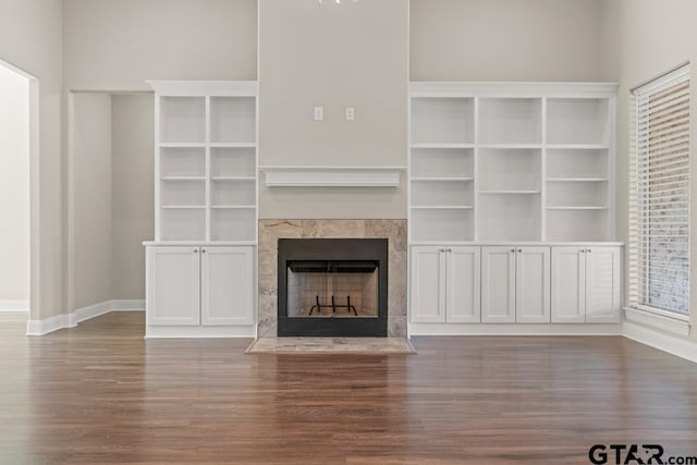 unfurnished living room with wood-type flooring and a tiled fireplace