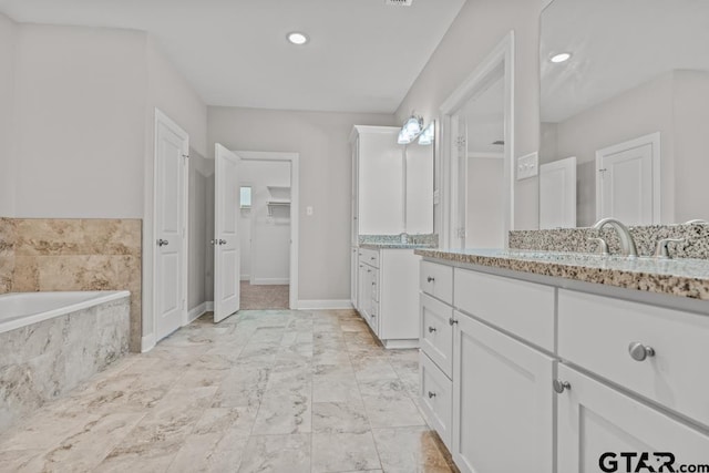 bathroom with vanity and tiled tub