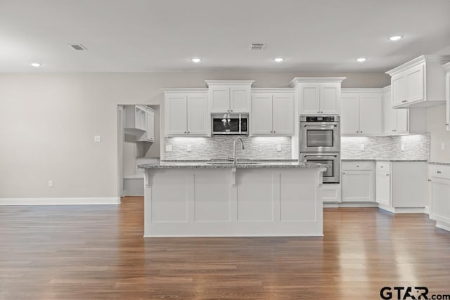 kitchen featuring white cabinetry, light stone counters, stainless steel appliances, and wood-type flooring