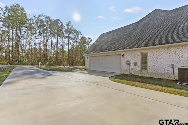 view of property exterior with central AC unit and a garage