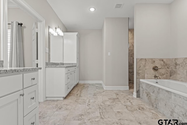 bathroom featuring vanity and tiled bath