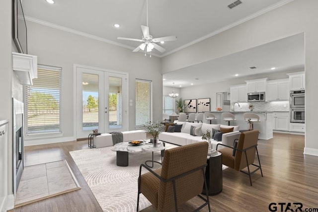 living room featuring ornamental molding, ceiling fan with notable chandelier, dark wood-type flooring, and sink