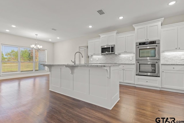 kitchen with white cabinets, a kitchen island with sink, and appliances with stainless steel finishes